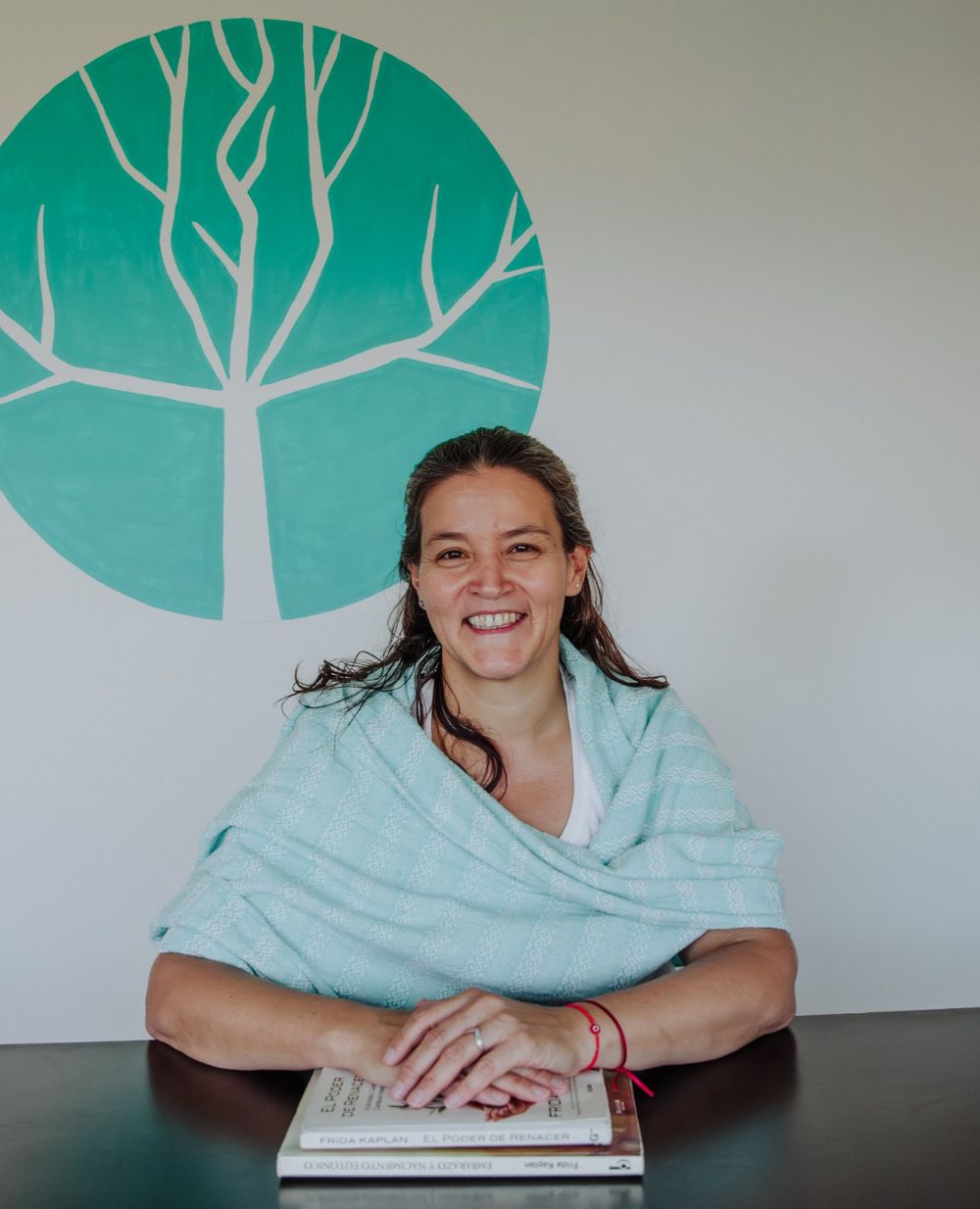 Débora Clavé sonriendo en su consultorio, con las manos sobre dos libros